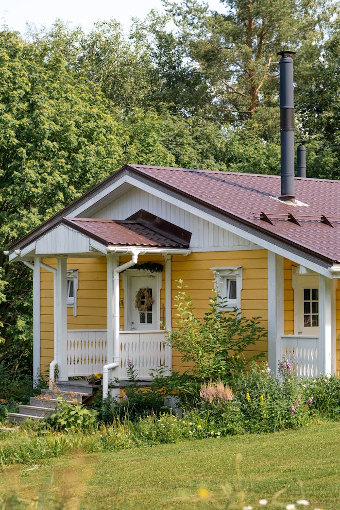 Idyllic yellow country house with a welcoming porch surrounded by lush greenery.